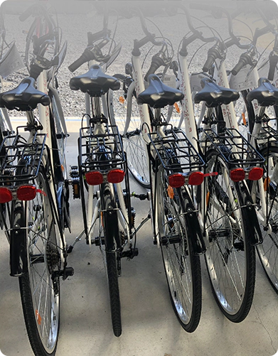 Row of bicycles parked indoors, focusing on rear view with visible red taillights.
