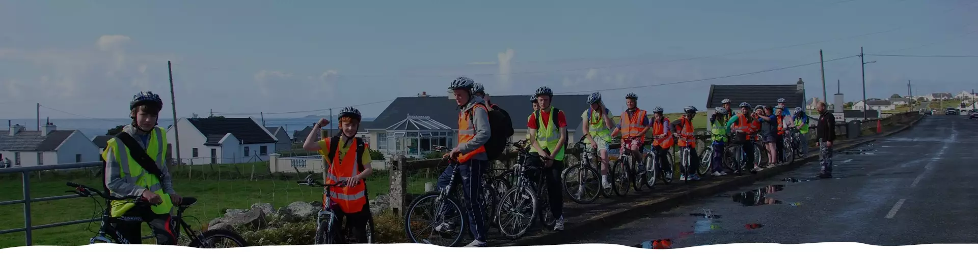 Cyclists with high visibility jackets resting by the road on a sunny day.