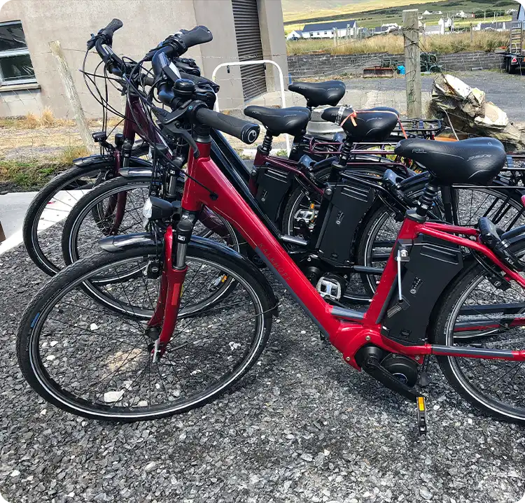 Red electric bike among other bicycles on a gravel surface.